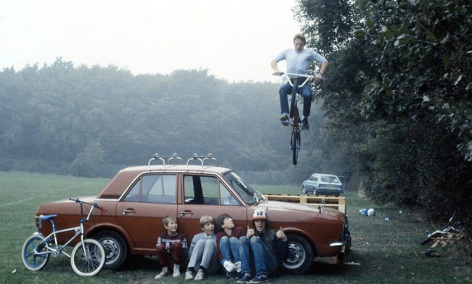 bmx bike catching air off a jump ramp leaning on a car